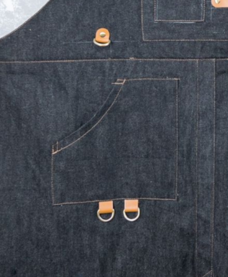 BBQ apron with main utility pocket featuring a corner cutaway for easy access and two D-rings for hanging BBQ accessories.