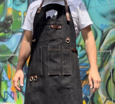Chef wearing a BBQ apron standing in front of a colourful graffiti wall.