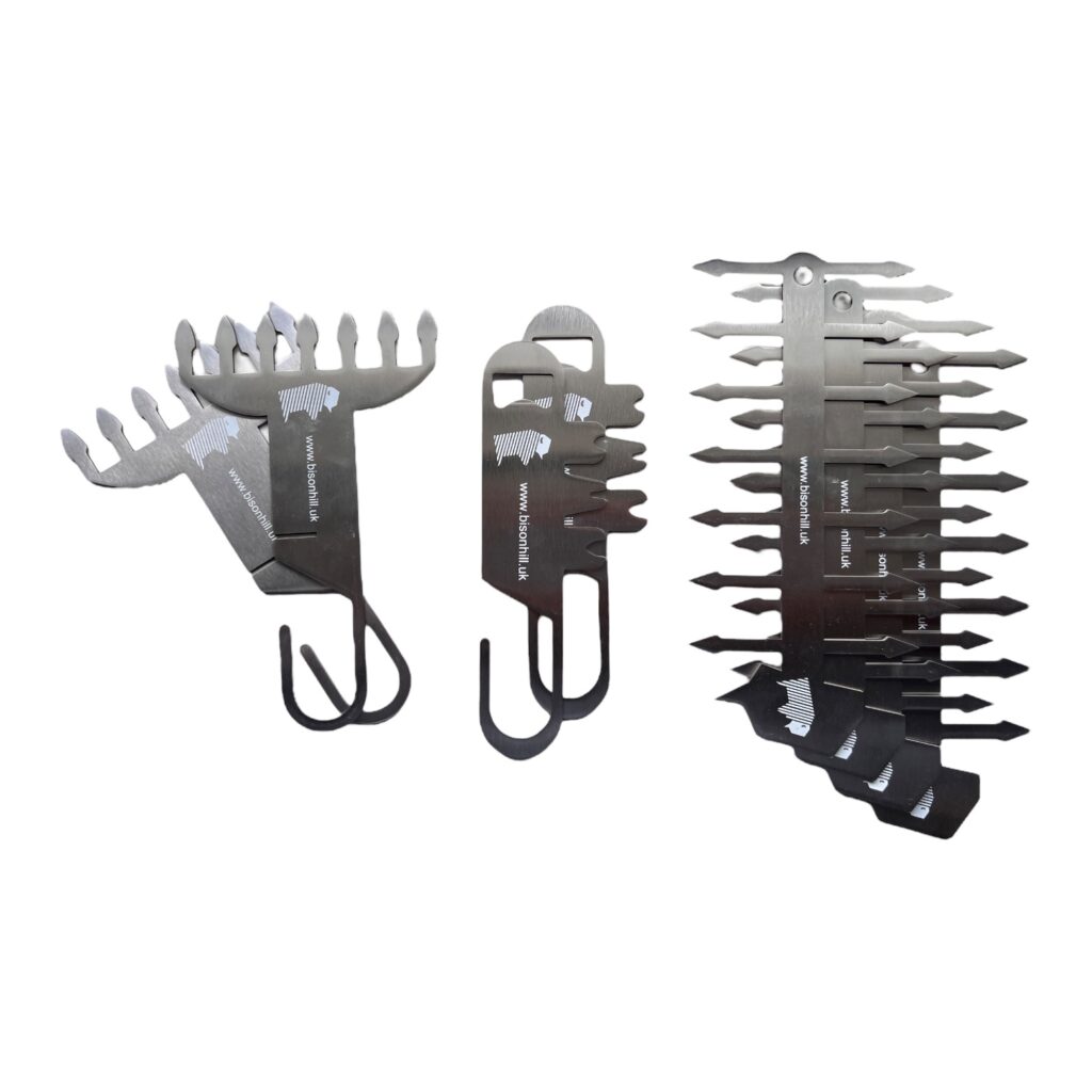 Three BBQ tools arranged side by side, including a meat shredder, grill scraper, and a skewer made from stainless steel.