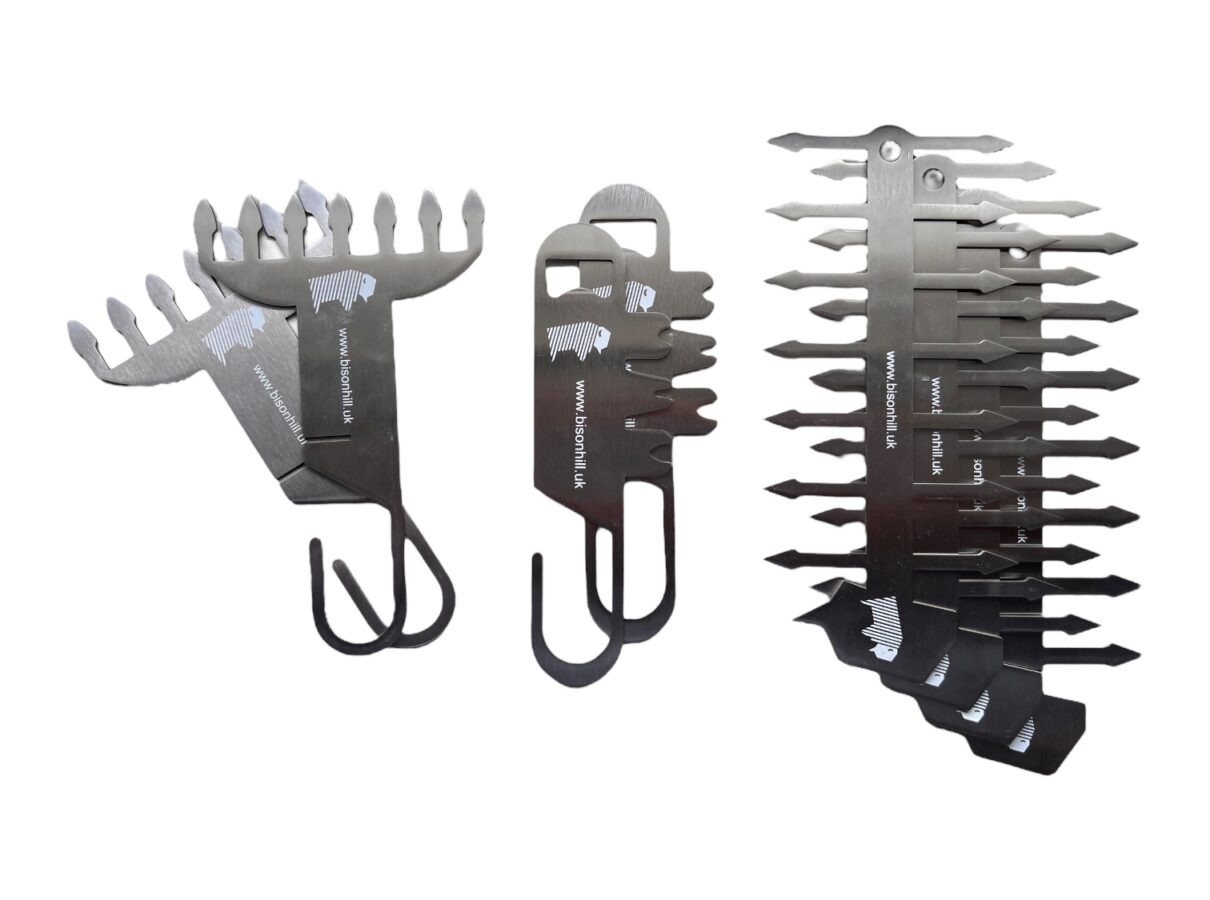 Three BBQ tools arranged side by side, including a meat shredder, grill scraper, and a skewer made from stainless steel.