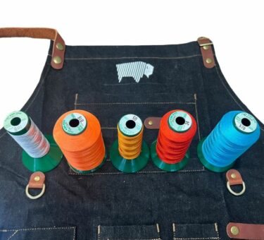A Bison Hill BBQ Apron made of denim displayed with five different coloured threads for personalisation options.