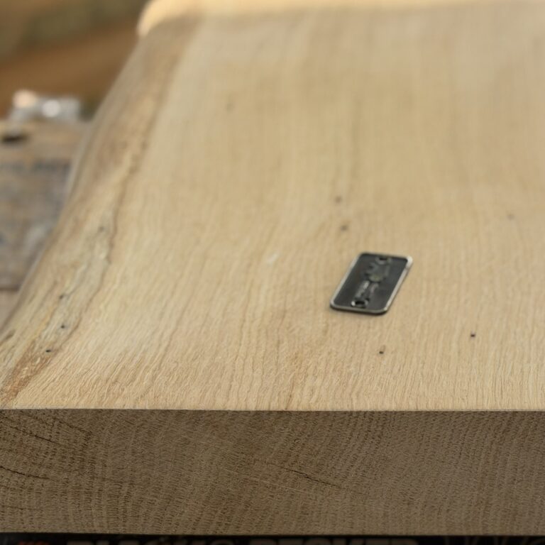 Close-up side profile of a thick solid oak chopping board showing the end grain growth rings and a smooth, level cutting surface.