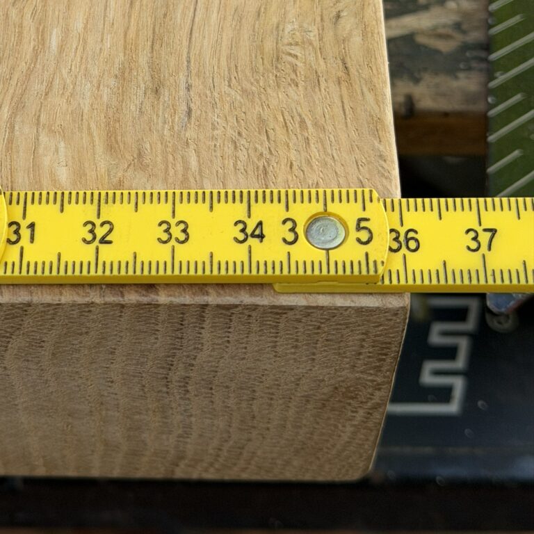 A yellow folding rule measuring the 35.5cm width of a solid oak live edge chopping board.