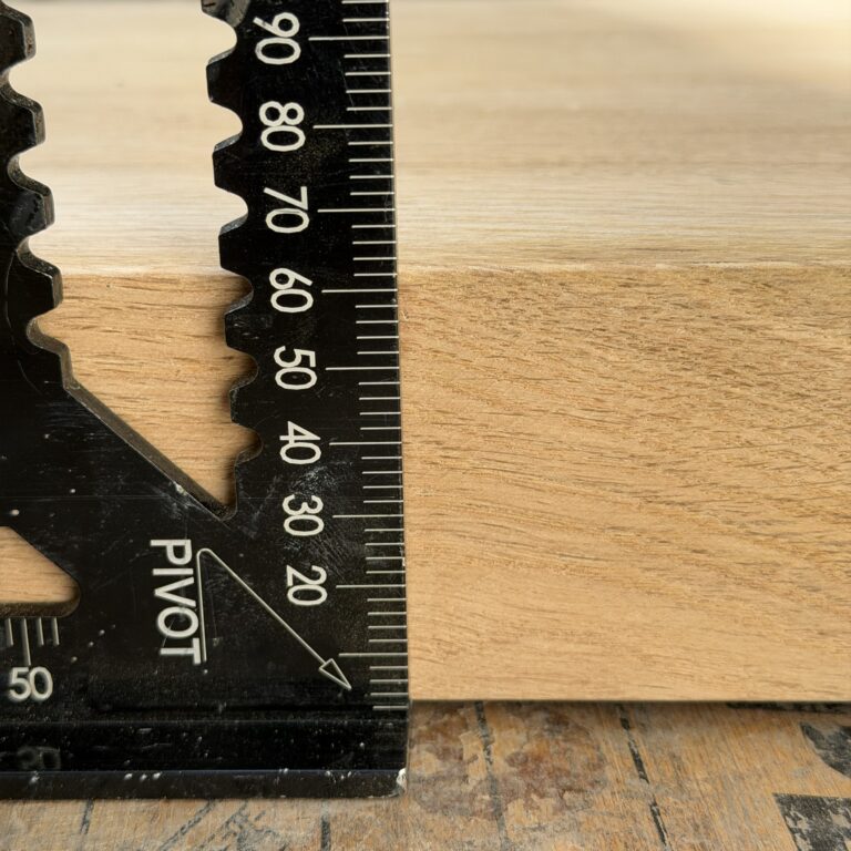 A metal engineering square measuring the massive 70mm thickness of a premium solid oak BBQ block.