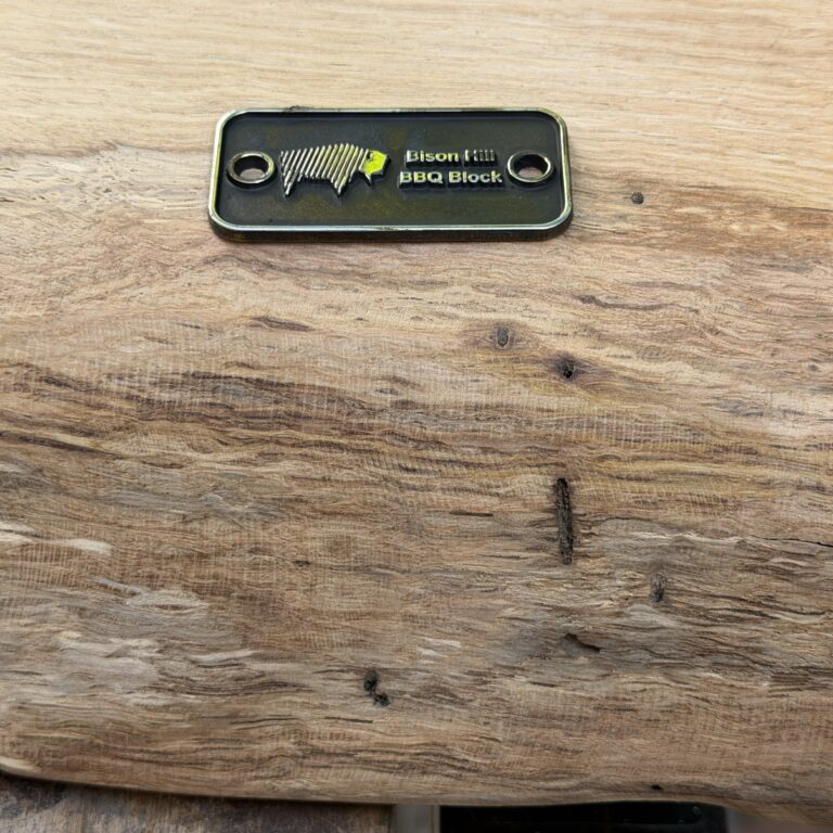 Macro view of the rounded live edge slope on a solid oak chopping board, showing rays and flecks in the wood grain.