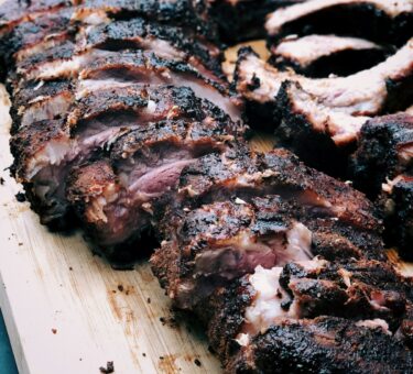 Flat metal skewers with chicken and vegetable kebabs on a charcoal grill